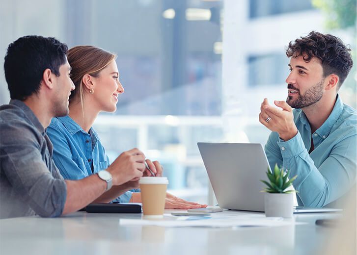 man with laptop talking to couple