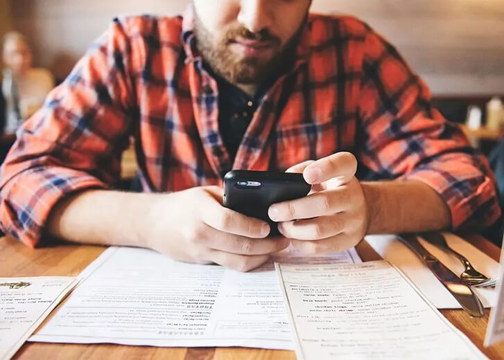 man with phone looking at budget