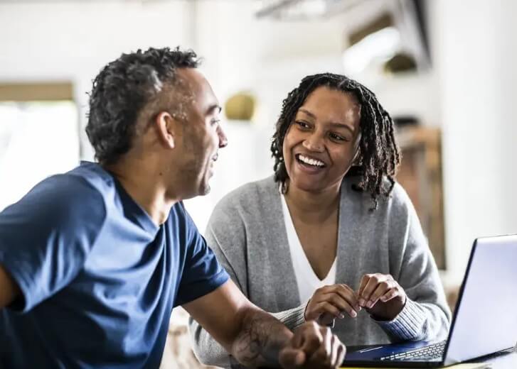 couple looking at each other with laptop