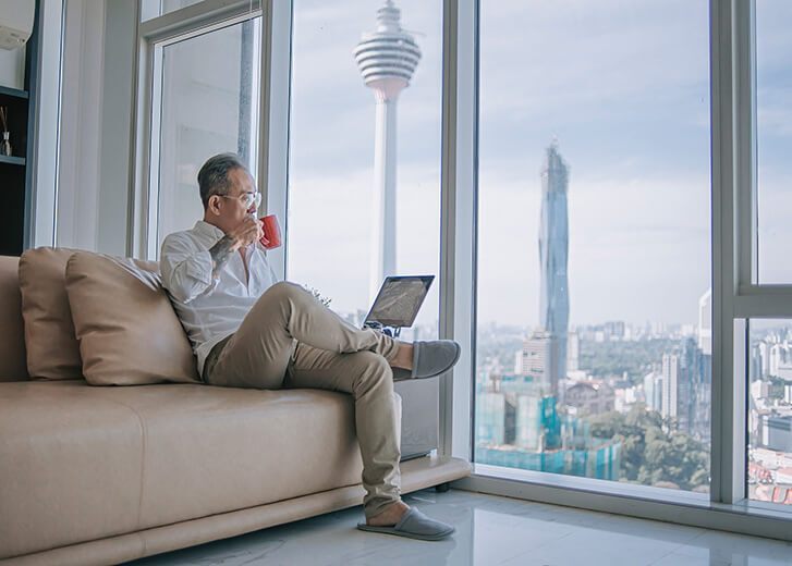 man on couch with mug and laptop