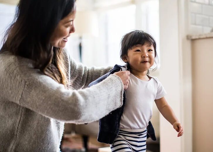 woman dressing child