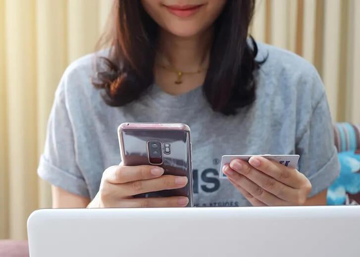 woman looking at phone and laptop